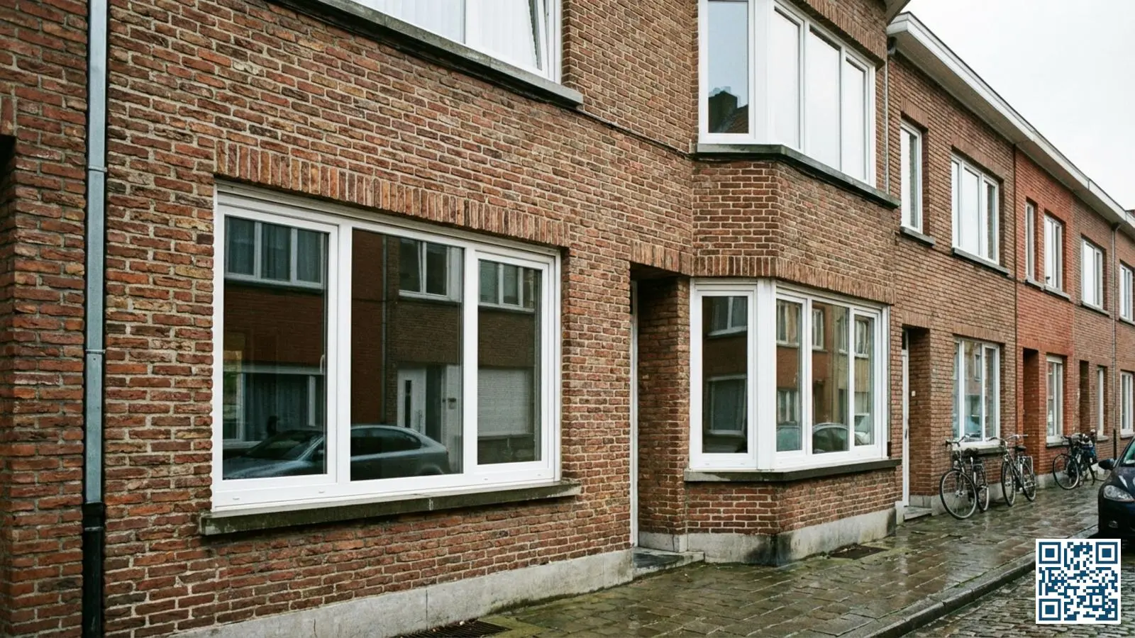 Belgische rijwoning met nieuw geplaatste HR-glas ramen in witte PVC-kozijnen op een zonnige dag